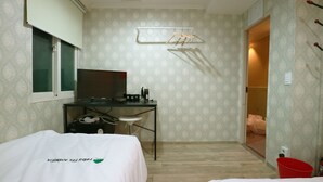 Habitación de hotel con cama, escritorio con televisor, un cubo rojo y armario.