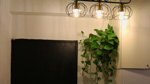 Un pasillo con una puerta negra, una escalera y una planta colgante.