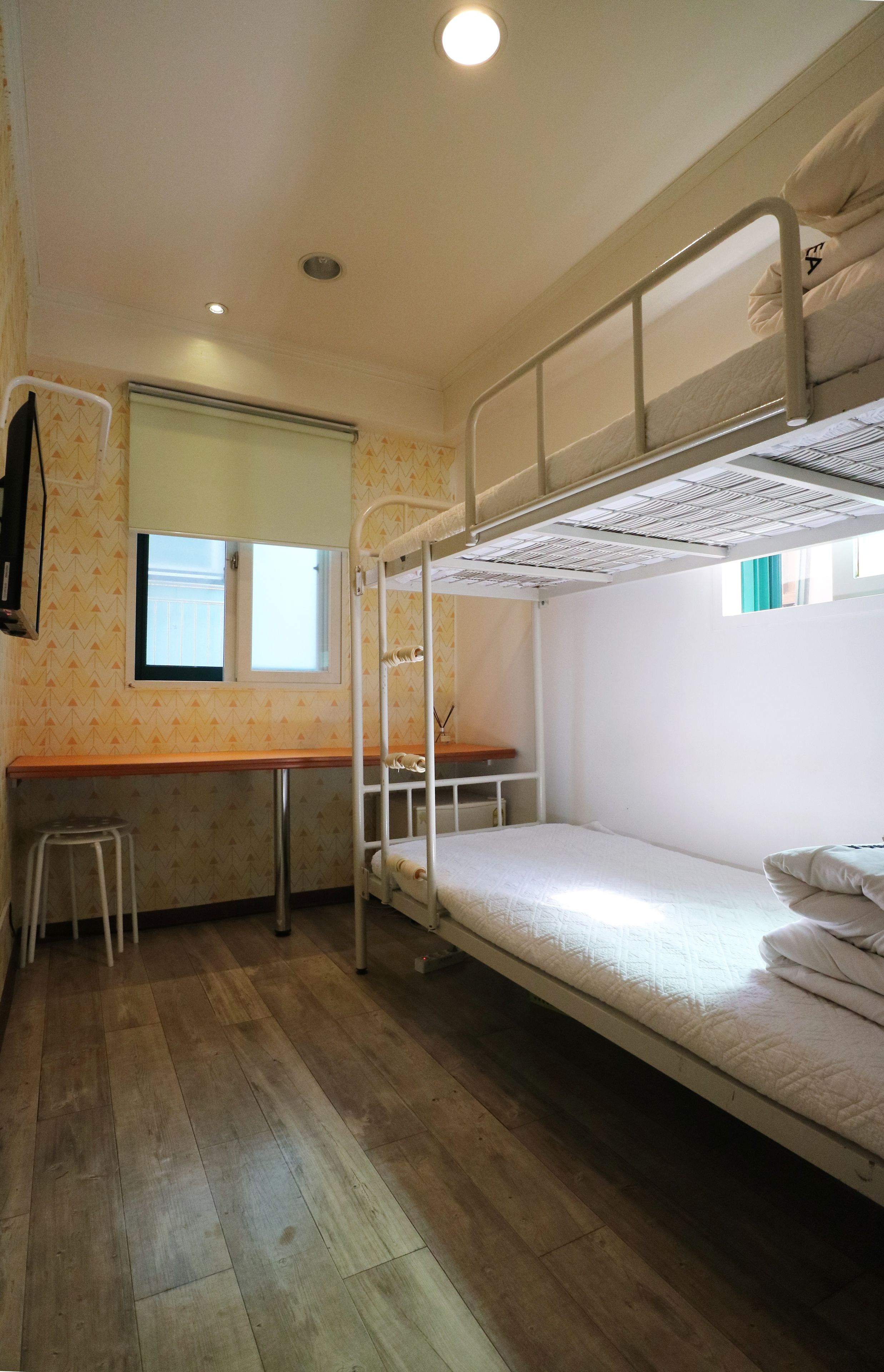 Quarto com beliche, escrivaninha e janela.