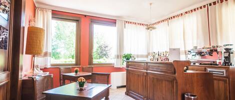 A kitchen with wooden cabinets, a dining table with chairs, a window with curtains, and a radiator.