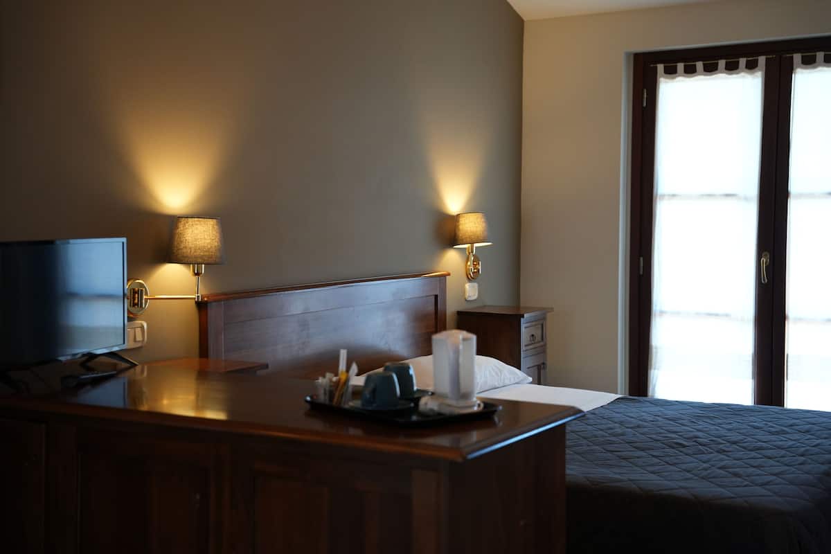 Une chambre d’hôtel avec un lit, une table de chevet, une lampe et un téléviseur.