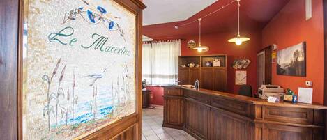 Un espace d’accueil agrémenté d’une œuvre d’art en mosaïque, d’un comptoir d’accueil en bois et d’un éclairage suspendu.
