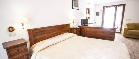 A bedroom with a wooden bed, bedside tables, a TV, and a sofa.