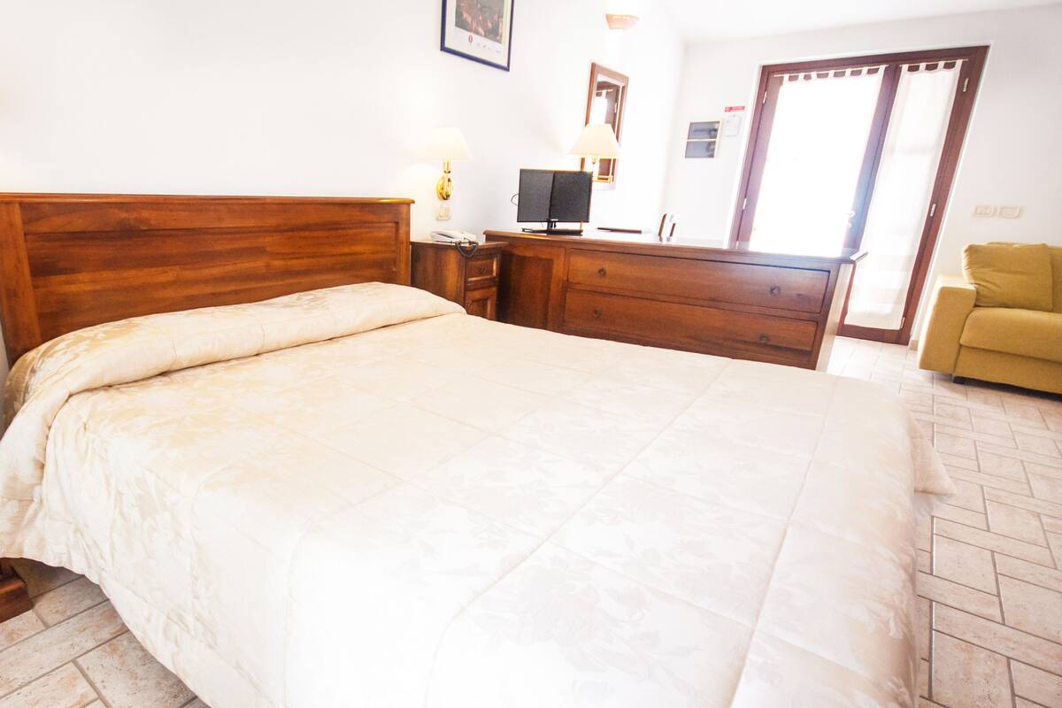 Une chambre bien rangée, avec un grand lit, des tables de chevet en bois, un bureau et une chaise.