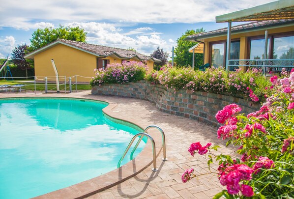 Una piscina al aire libre, sombrillas, sillones reclinables de piscina