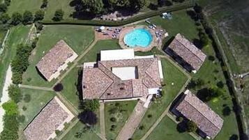 Vue aérienne d’un quartier résidentiel comprenant quatre maisons, une piscine et un grand espace ouvert.