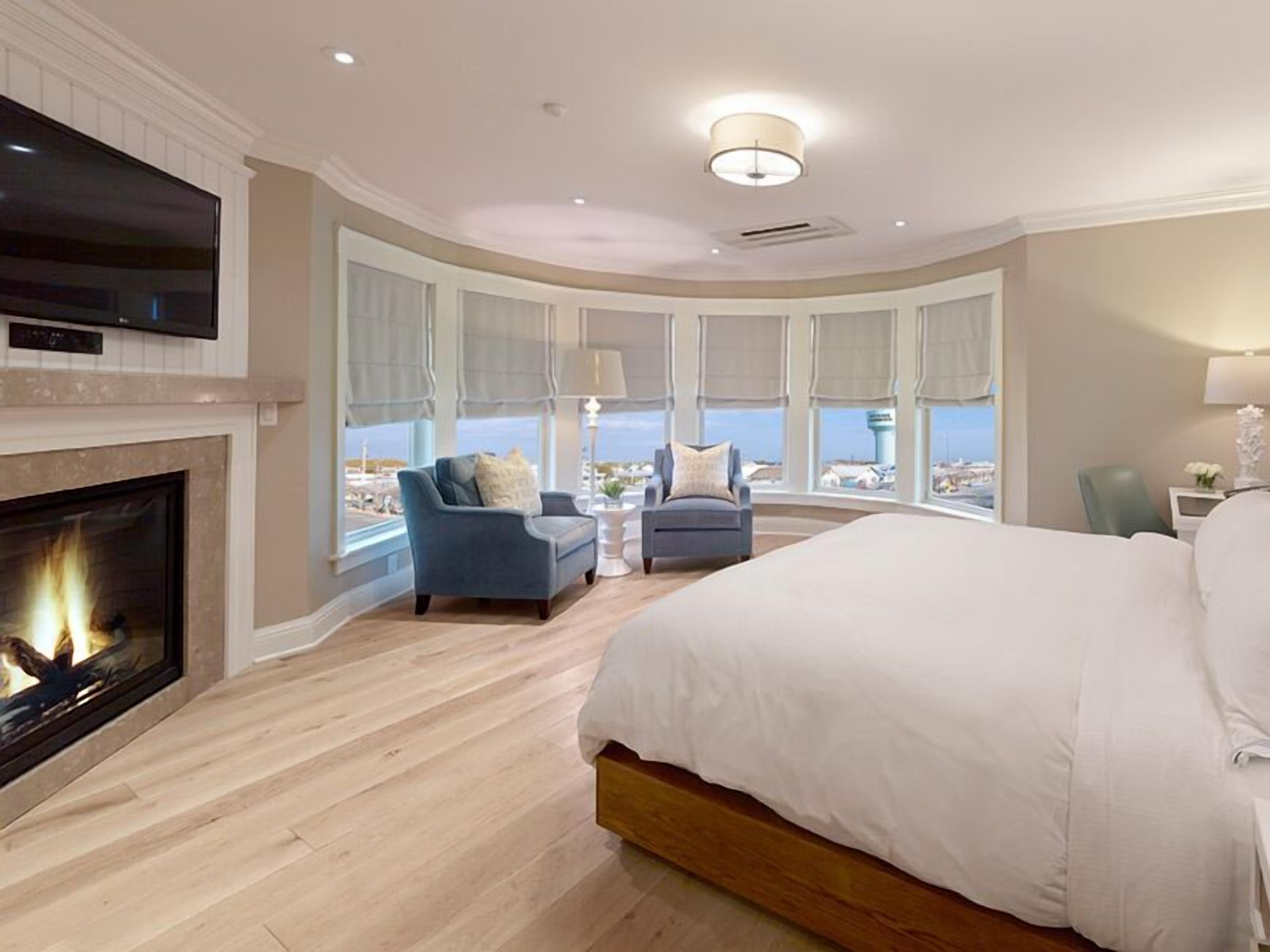 Ein Hotelzimmer mit einem großen Bett, einem Kamin, einem Fernseher und Blick auf die Stadt.