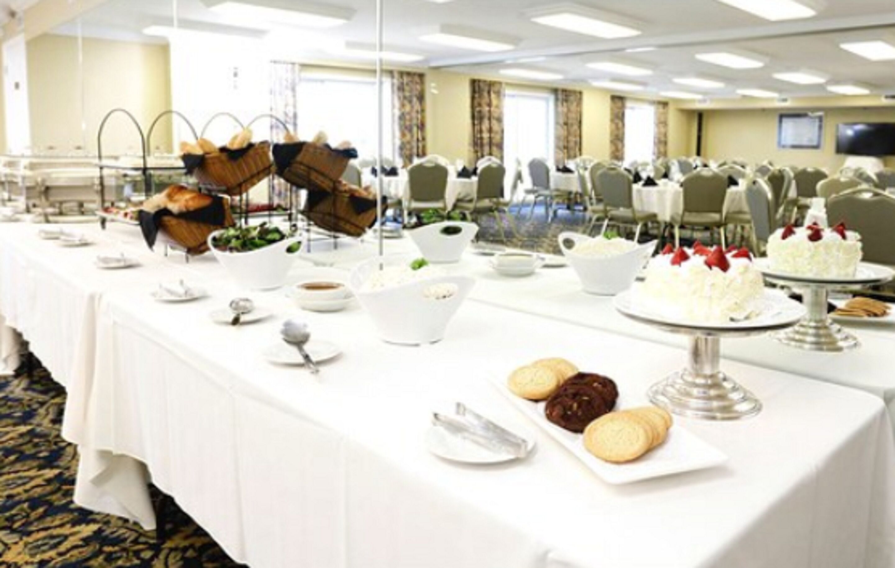 Un buffet proposant divers plats et un gâteau, le tout disposé sur une longue table dans une salle de conférence.