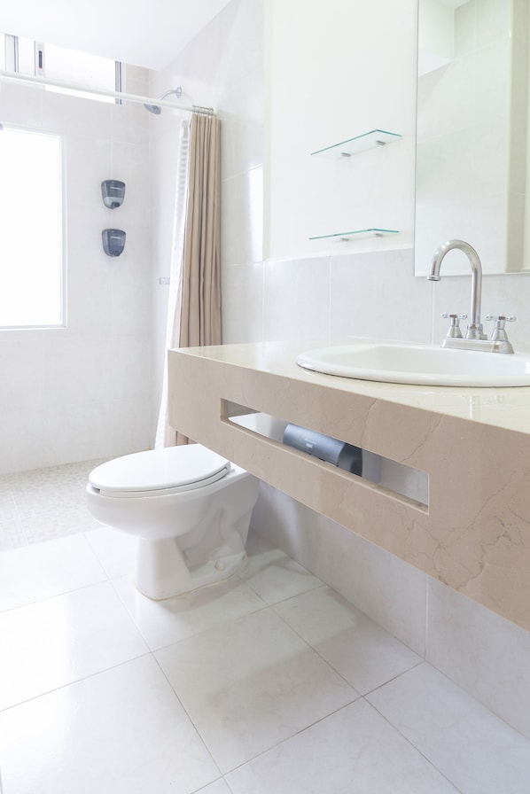 Un baño moderno con inodoro, lavamanos y ducha.