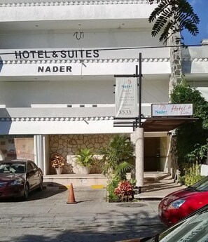 Ένα ξενοδοχείο με το όνομα «Nader Hotel & Suites», με πρόσοψη από πέτρα και μια επιγραφή που διαφημίζει τις υπηρεσίες «Ξενοδοχείο & Σουίτες» και «Nader Hotel & Suites».