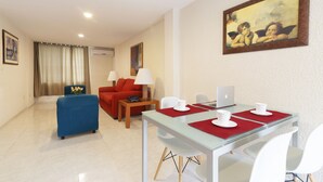 A modern hotel room with a dining area, a sofa, a coffee table, and a painting on the wall. - Hotel & Suites Nader (Cancun)