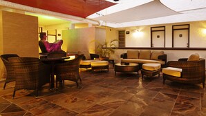 A lobby with wicker furniture, a sofa, and a potted plant. - Hotel & Suites Nader (Cancun)