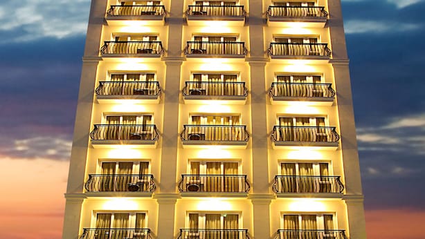 Un hotel de diverses plantes amb balcons, un rètol que diu “GOLDEN SAND Hotel” i una entrada ben il·luminada.