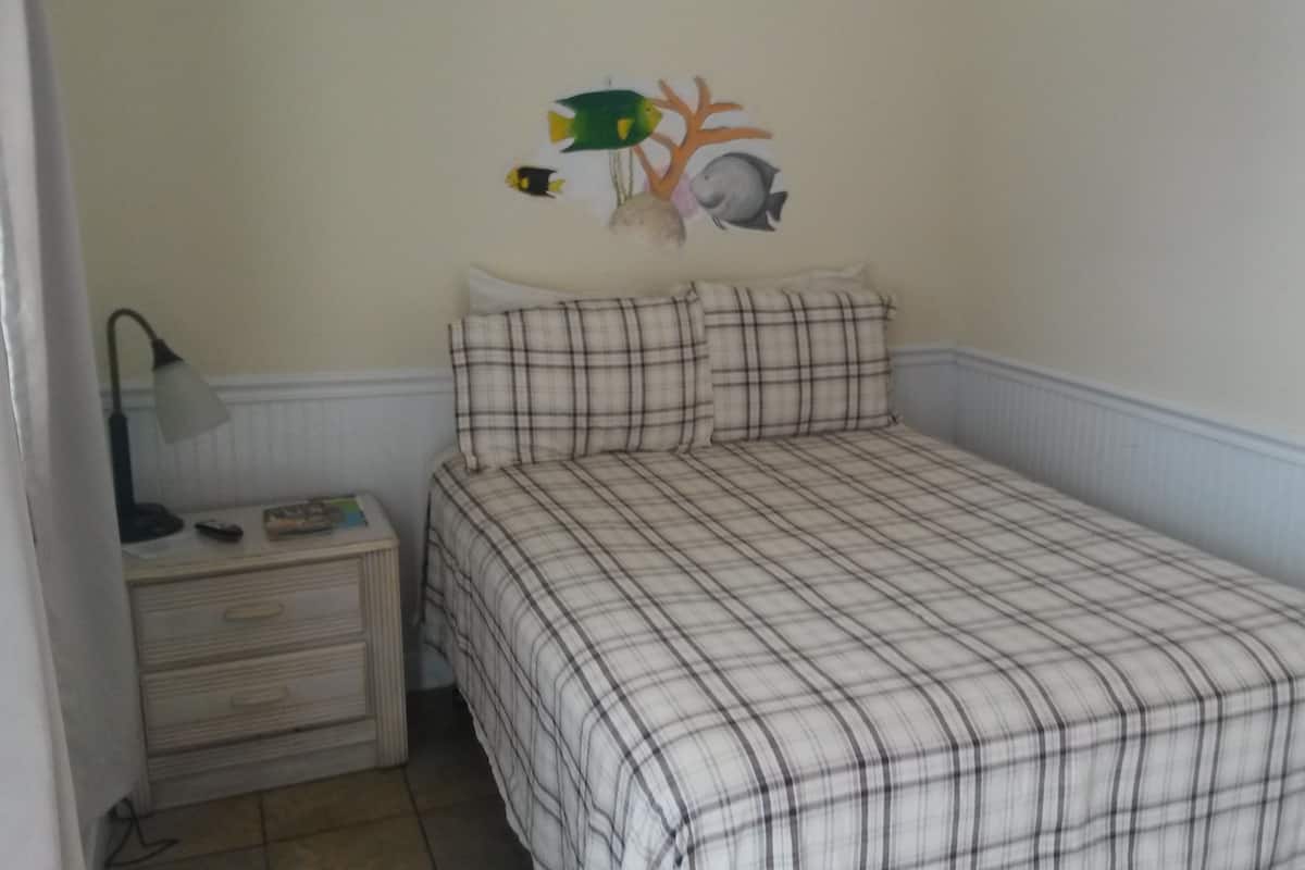 Une chambre à coucher comprenant un lit, une table de chevet, une lampe et un élément décoratif mural.