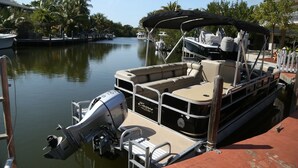 A motorboat docked at a marina with a covered seating area, a Honda outboard motor, and a wooden dock. - Conch On Inn Motel (Tavernier)