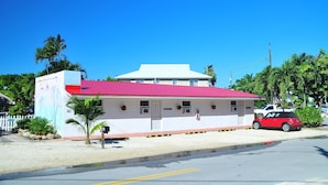A small building with a red roof, a white facade, and a red car parked in front. - Conch On Inn Motel (Tavernier)