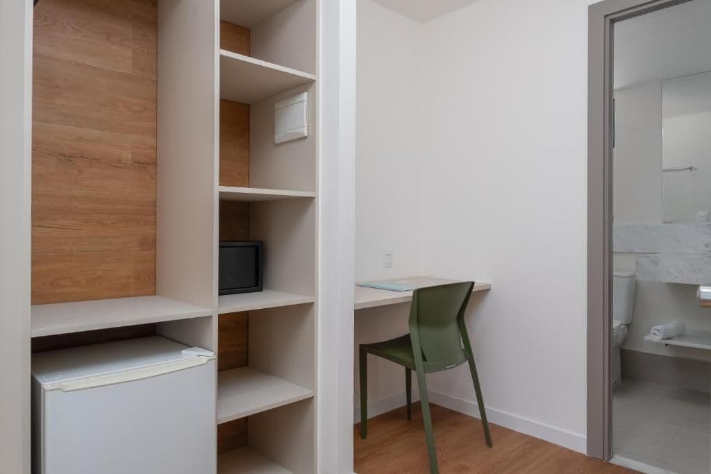A room with a desk, chair, and shelving unit.