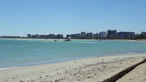 A beach with a city skyline in the background. - Poutur Pousada (Maceió)