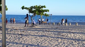 A sandy beach with people and a tree. - Poutur Pousada (Maceió)