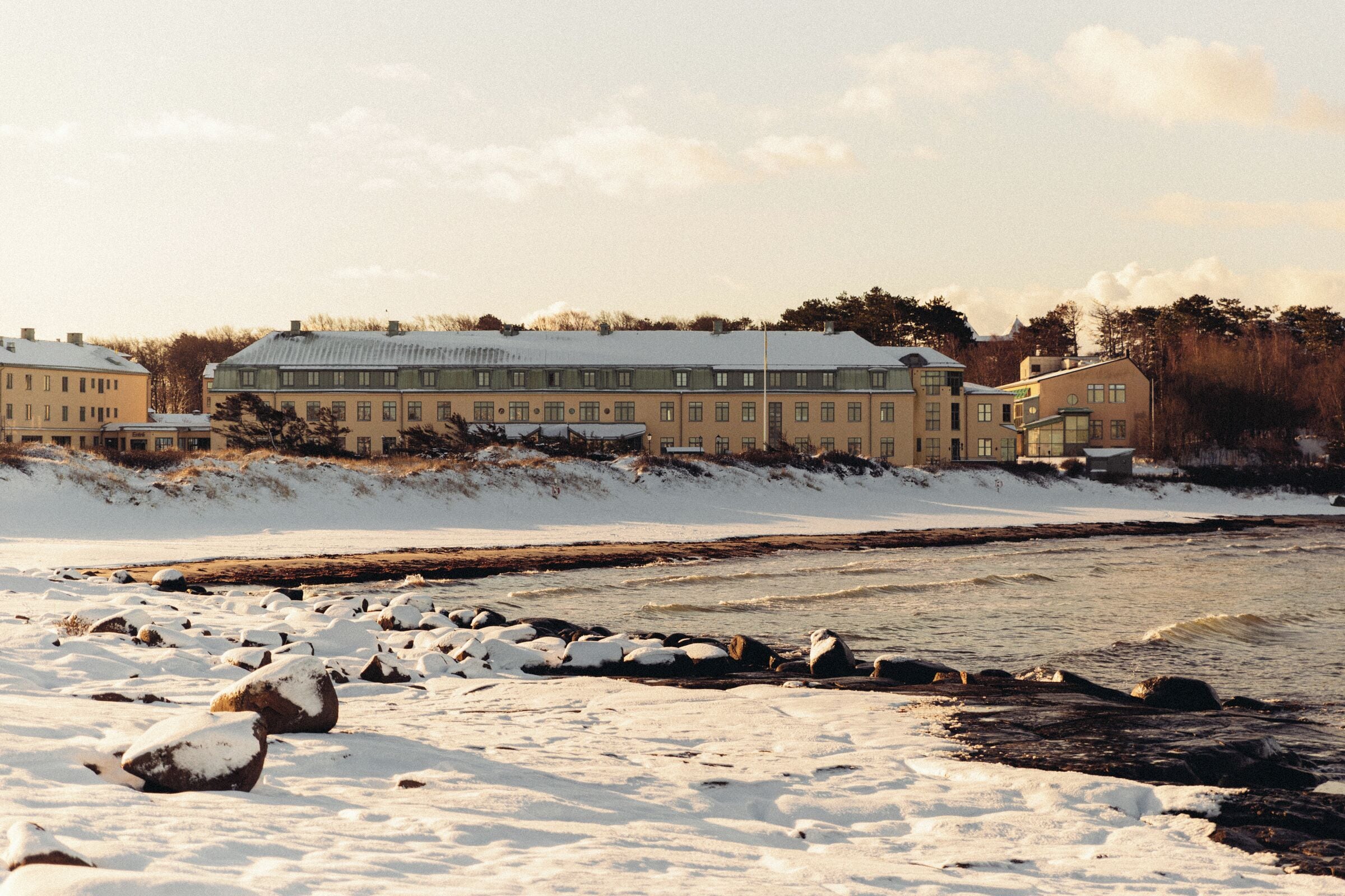 A large building with multiple windows and a snow-covered landscape.