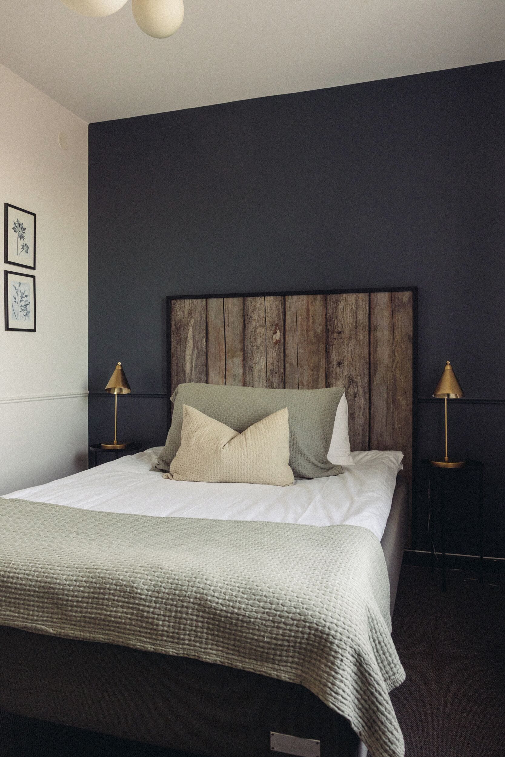 A neatly made bed with a wooden headboard, two bedside lamps, and a framed picture on the wall.