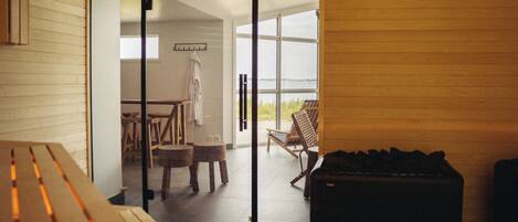 A modern interior with a wooden bench, a table, and a suitcase, leading to a balcony with a view.
