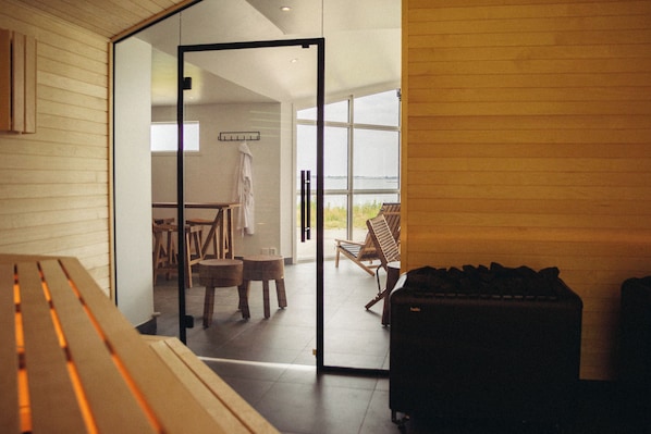 A modern interior with a wooden bench, a table, and a suitcase, leading to a balcony with a view. - Varbergs Kusthotell (Varberg)