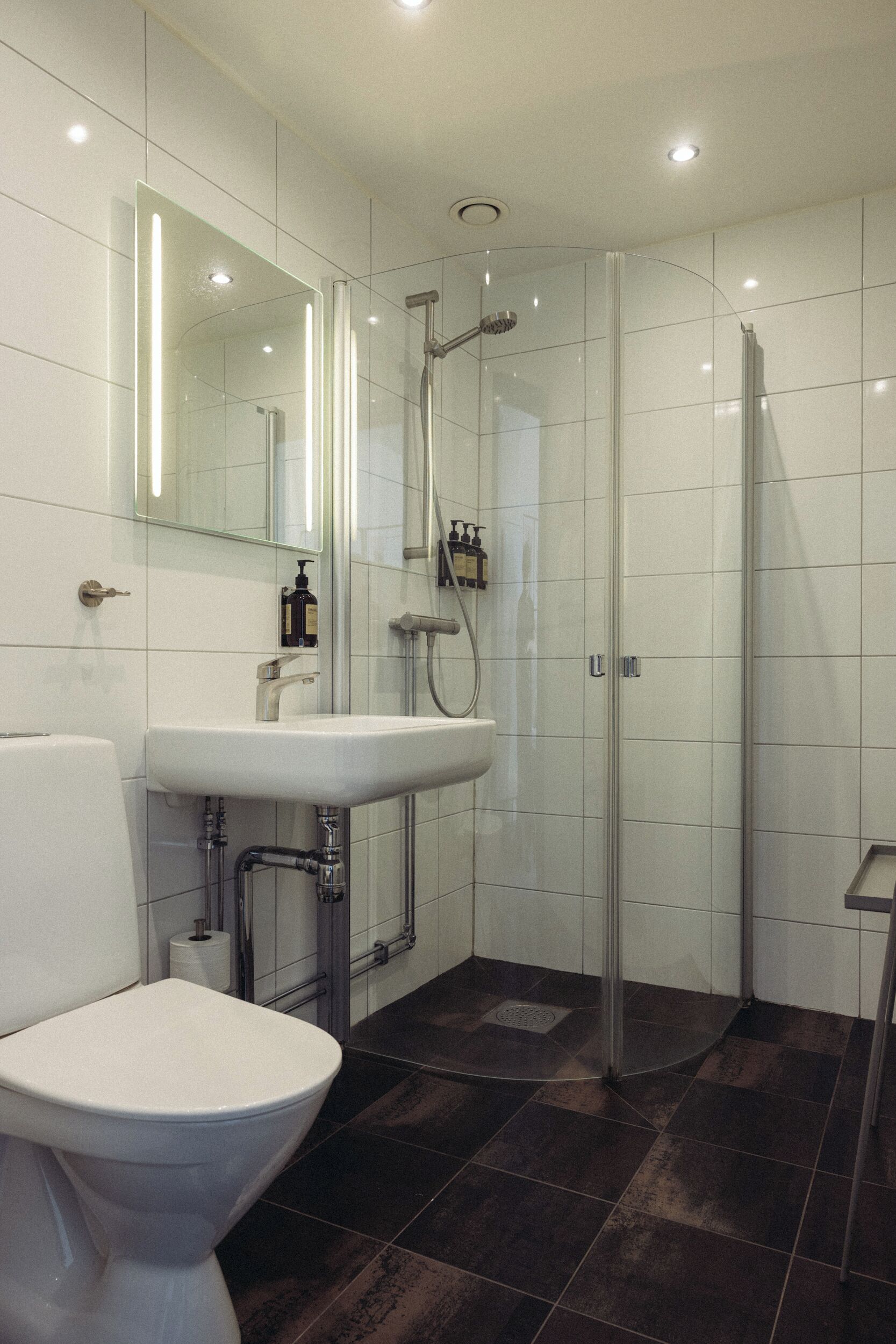 A modern bathroom with a toilet, sink, and glass-enclosed shower.