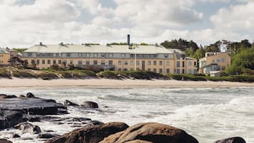A coastal hotel with a large building, rocky shoreline, and waves.