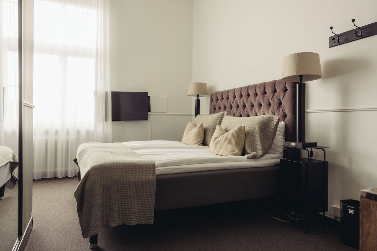Ein ordentlich eingerichtetes Schlafzimmer mit einem großen Bett, zwei Nachttischlampen, einem Flachbildfernseher und einer Heizung.