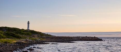 A lighthouse on a rocky coastline with a clear sky.