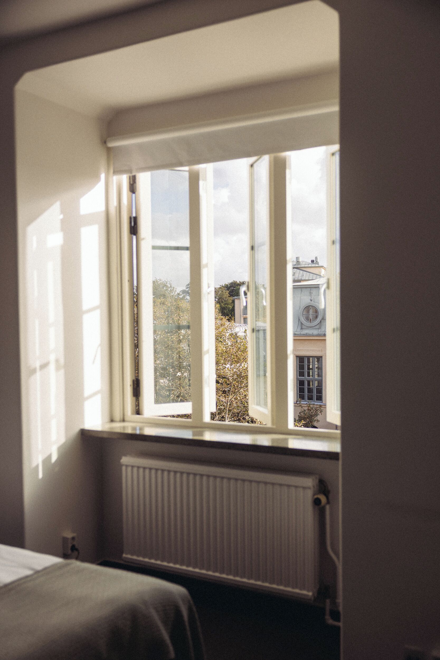 A room with a large window, a radiator, and a bed.