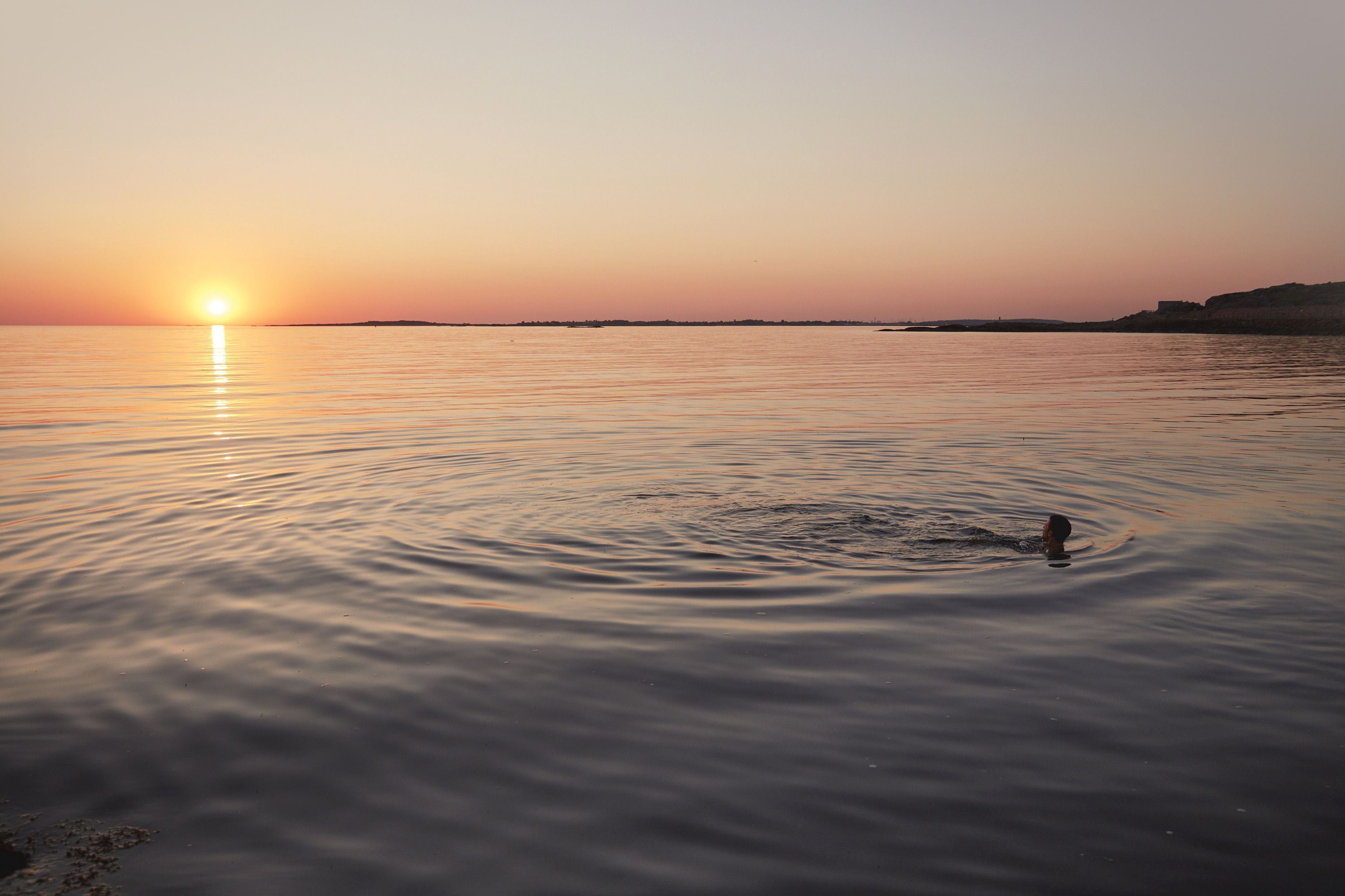 A calm body of water with a sunset in the background.