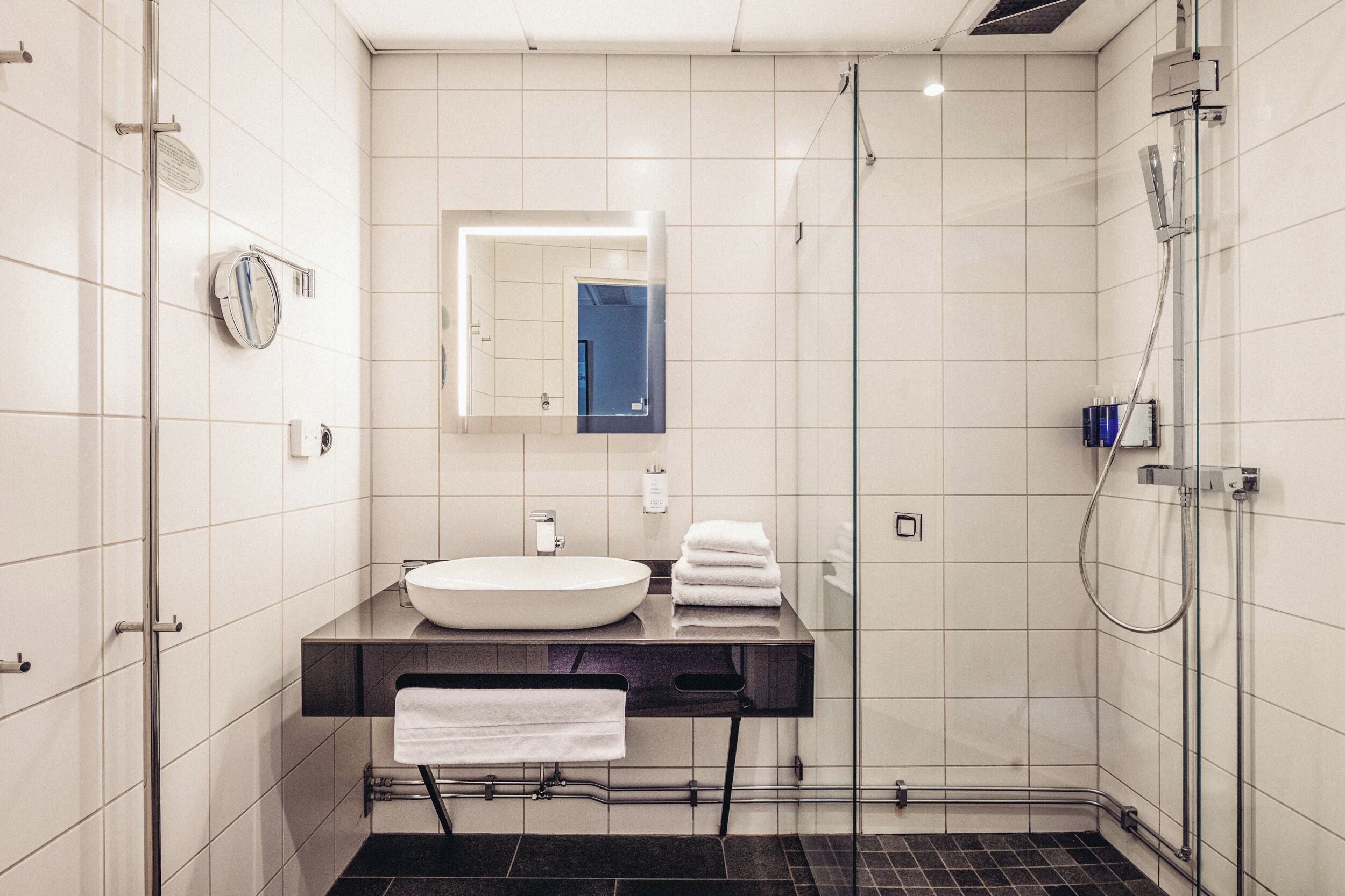 Un baño moderno con un espejo grande, un lavabo y una ducha.
