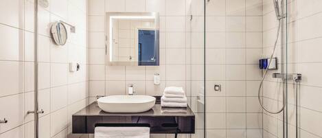 Un baño moderno con un espejo grande, un lavabo y una ducha.