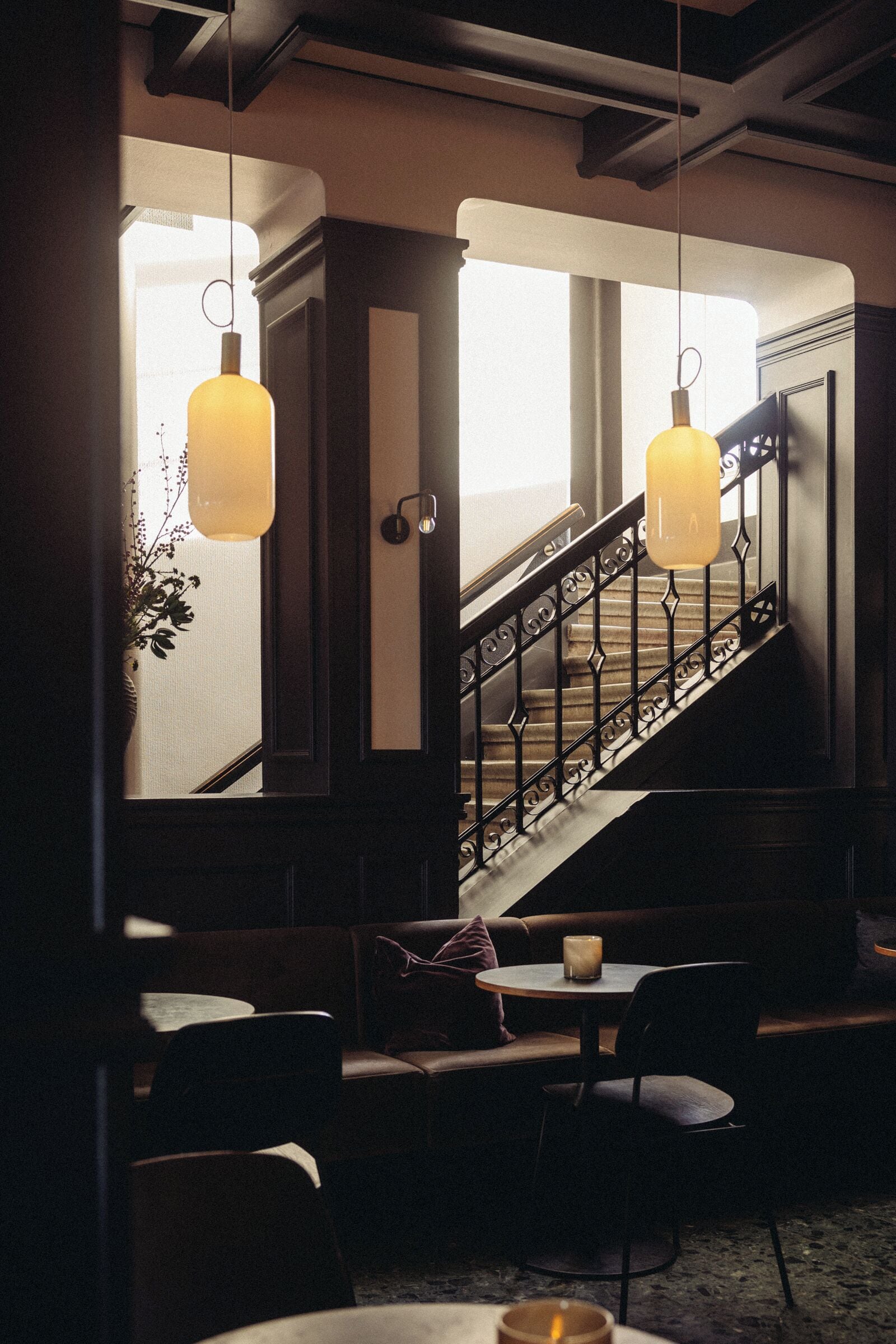 A cozy interior with a staircase, wooden banisters, and hanging pendant lights.