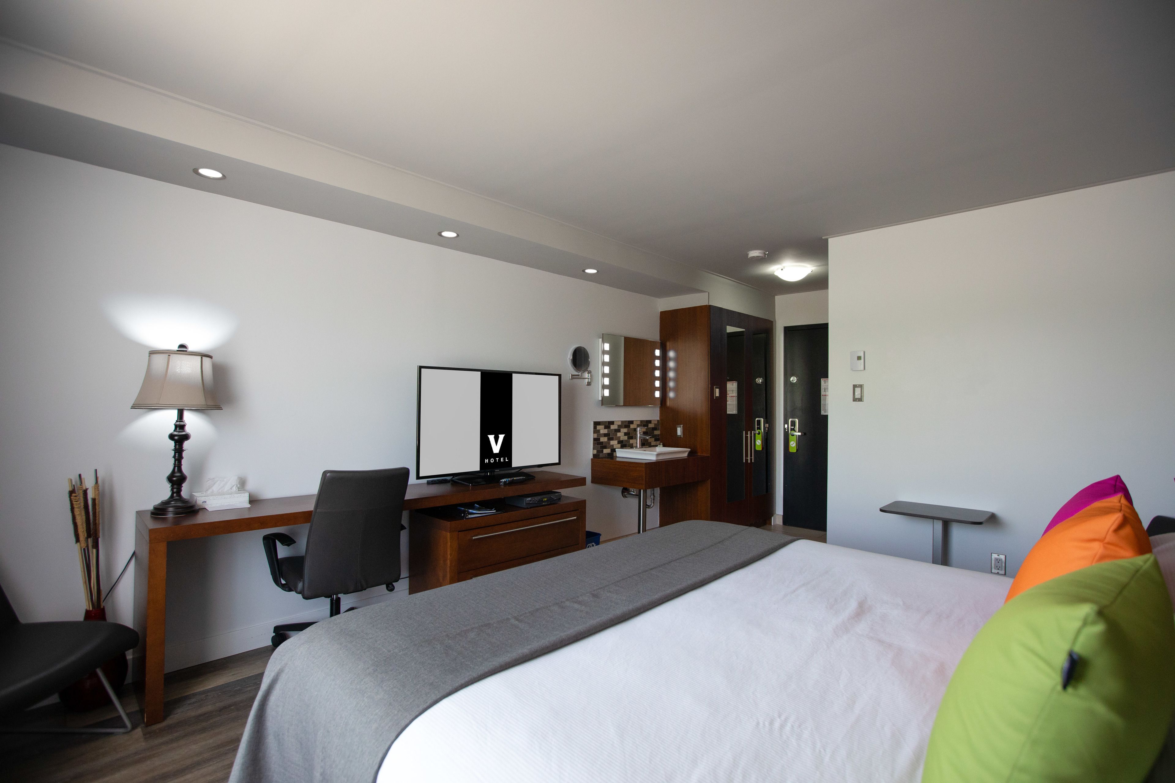 Une chambre d’hôtel équipée d’un lit, d’un bureau, d’une chaise, d’une lampe et d’une coiffeuse avec des miroirs.