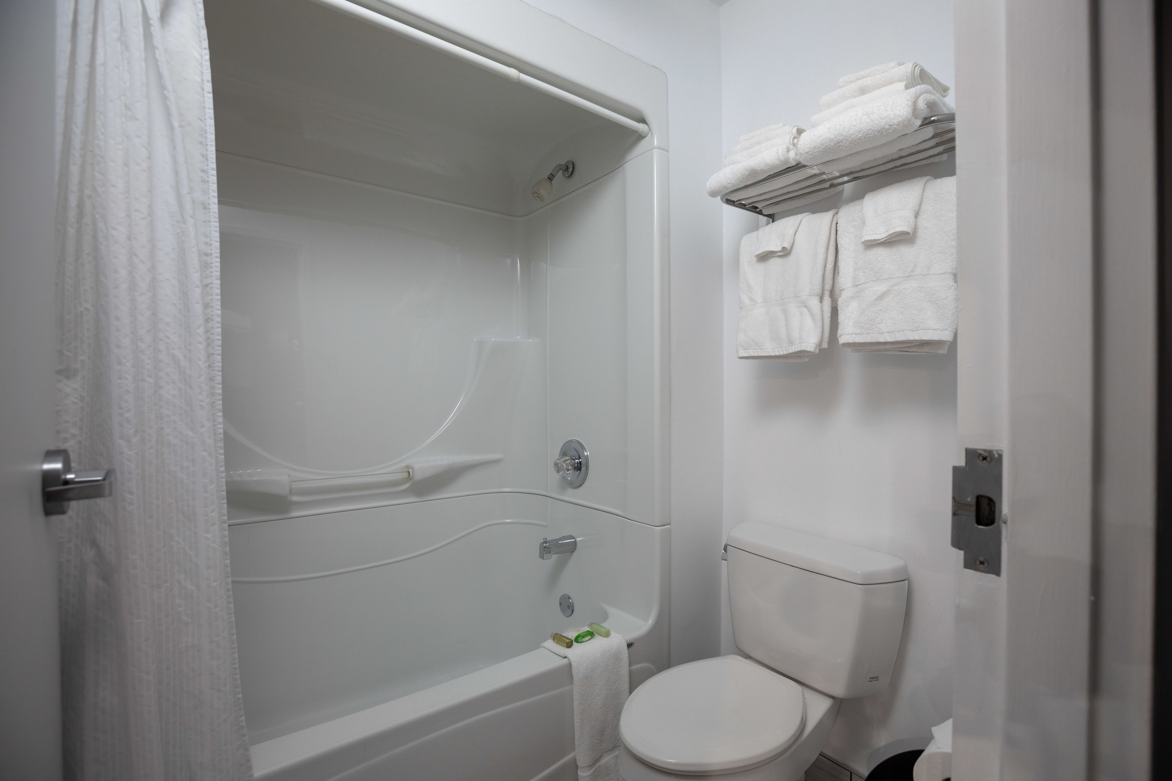 Un baño con bañera, inodoro y toallero con toallas dobladas.