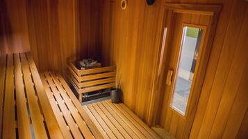 Un sauna de madera con bancos y un pequeño banco de madera con un cubo.