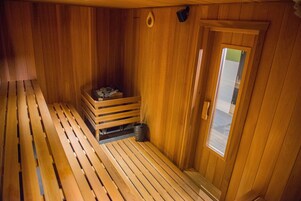 Un sauna de madera con bancos y un pequeño banco de madera con un cubo.