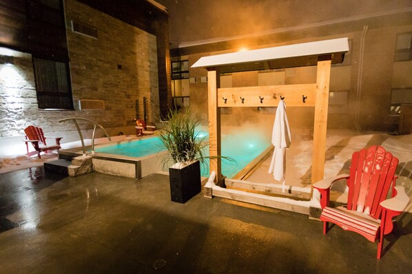 Un área de spa con un jacuzzi, un banco de madera y una silla roja.