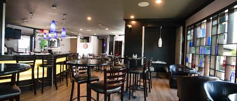 Een restaurant met houten vloeren, meerdere tafels en stoelen, en een bar.