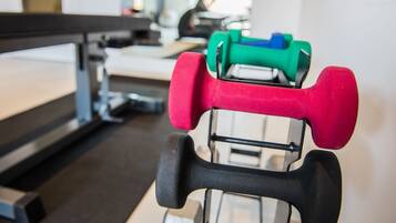 Uma academia com equipamentos de exercícios, incluindo halteres e um banco.