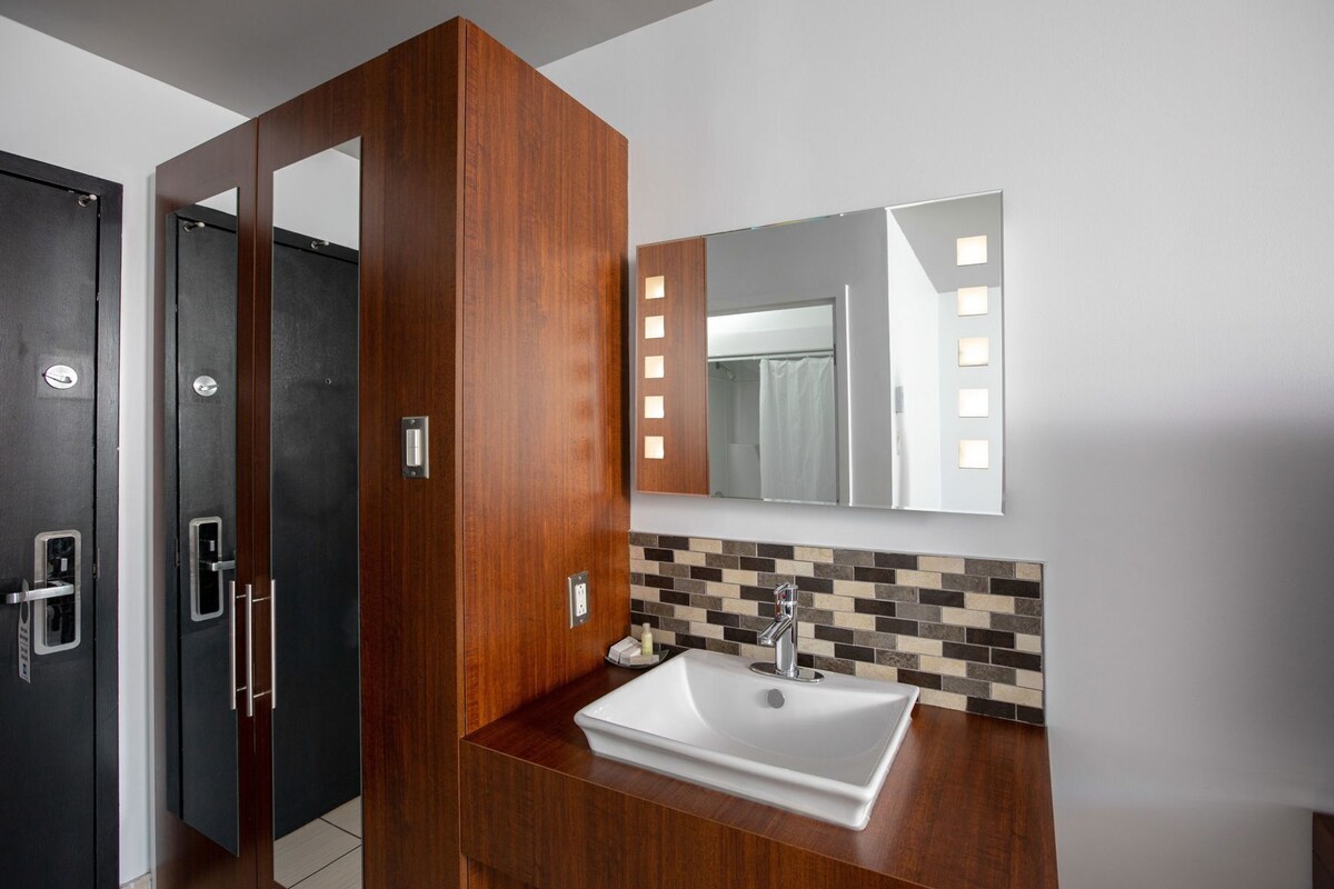 Un baño moderno con tocador de madera, un espejo grande y salpicadero de azulejos.