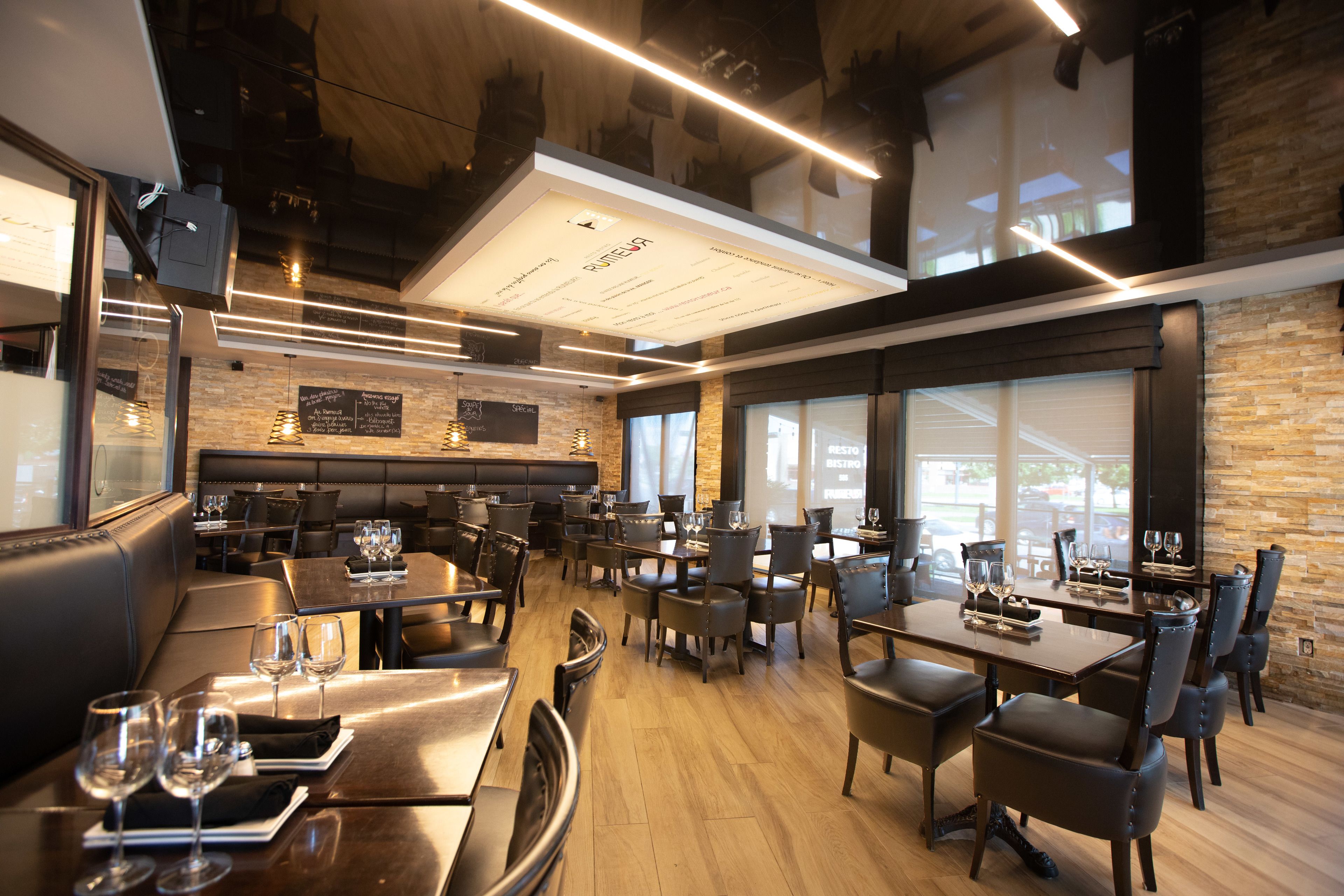 A modern restaurant with high ceilings, exposed beams, and a mix of seating options including booths and tables.