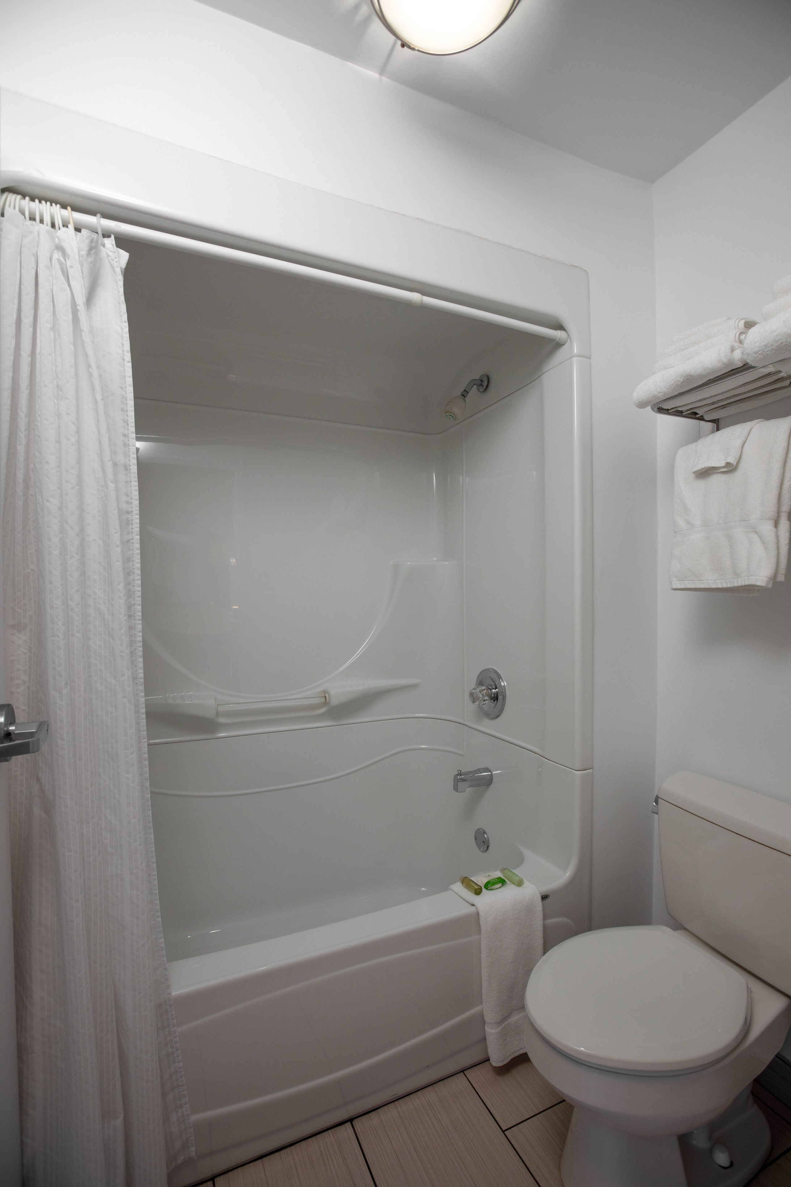 A bathroom with a bathtub, toilet, and a towel rack.