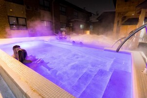 Piscina al aire libre climatizada con vapor, rodeada de edificios.