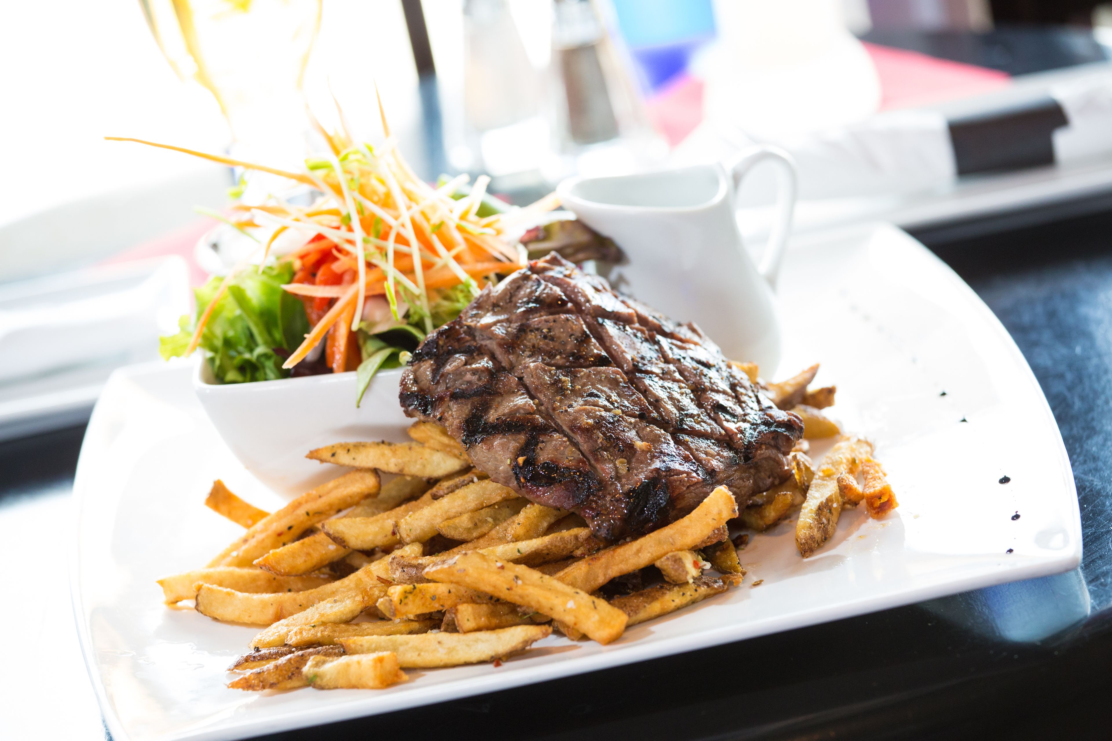 A plate with a steak, fries, and a side salad.