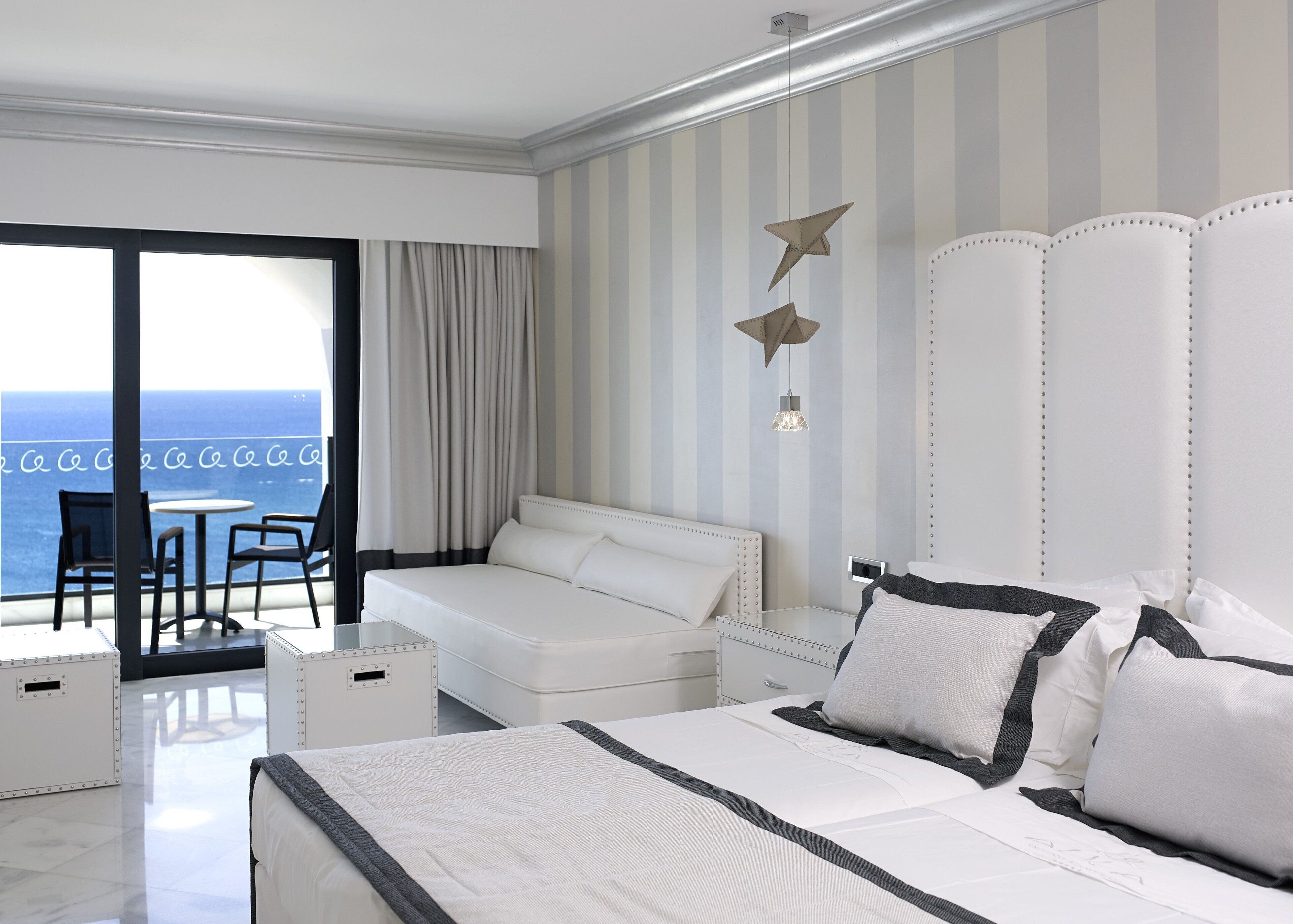 Habitación de hotel con cama, sofá, una mesita y vista al océano.