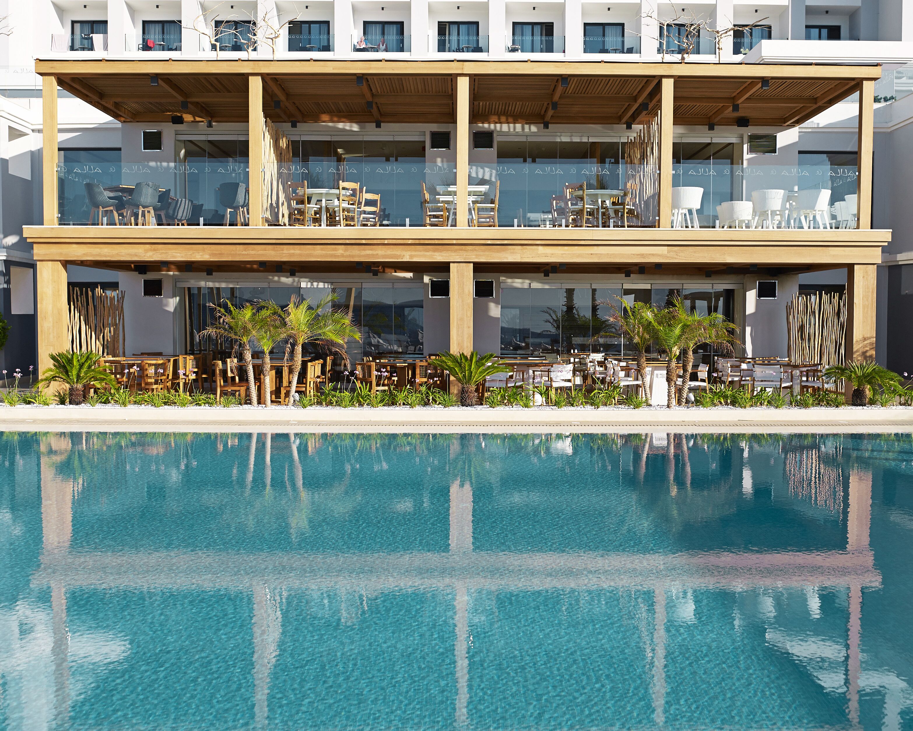 A modern hotel with a pool, outdoor seating, and a two-story structure.